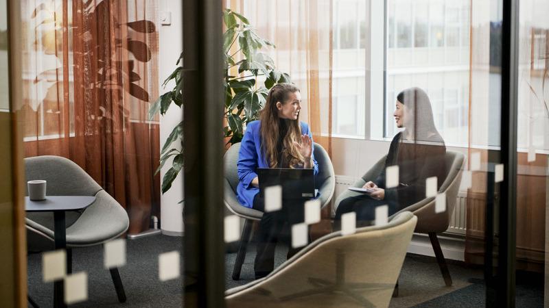 Two women discussing in a meeting room.