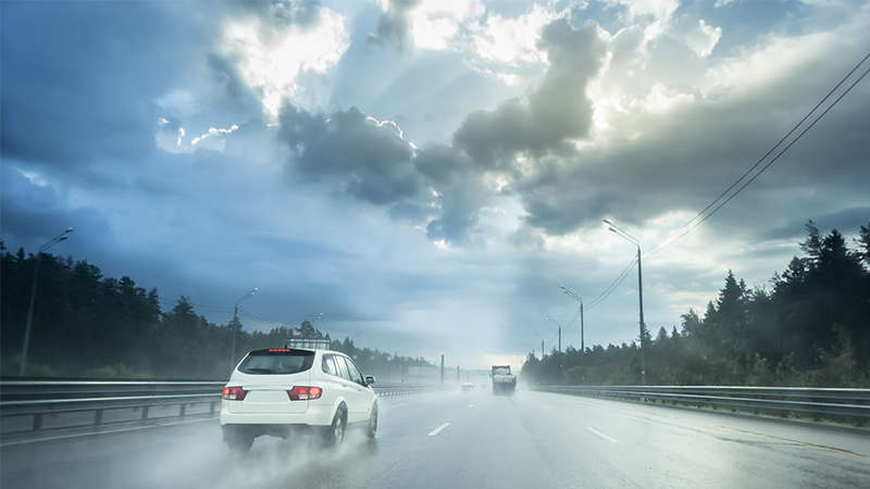 Drive car in rain on asphalt wet road. Clouds and sun.