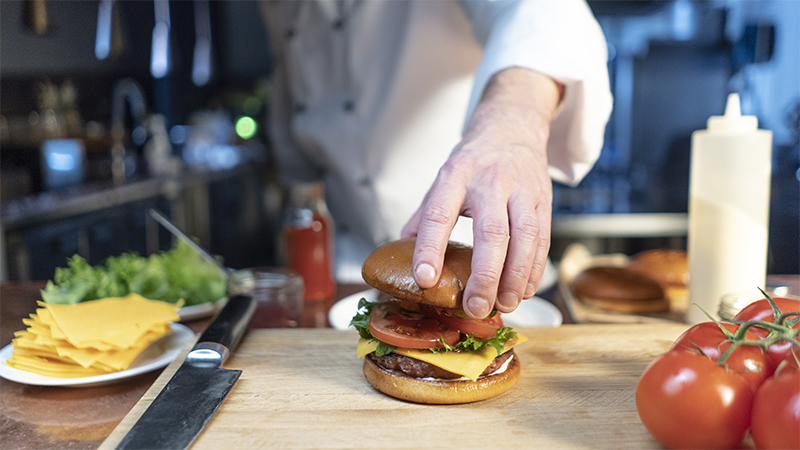 A chef assembling a hamburger