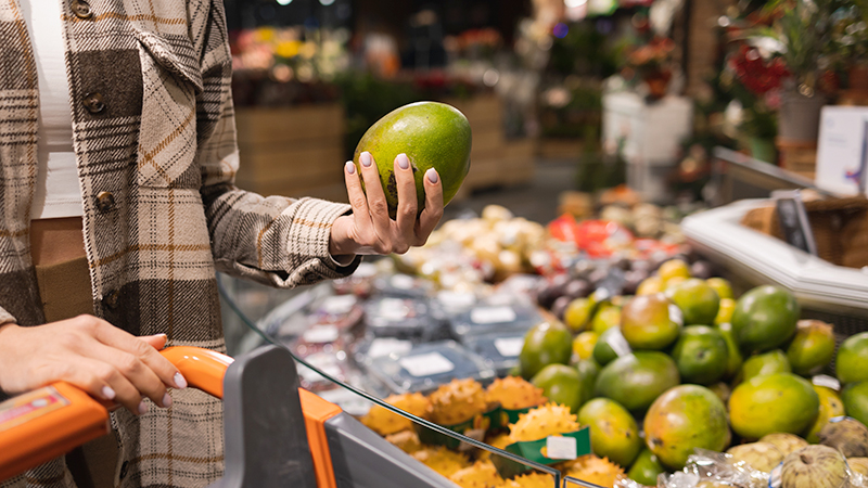 Woman choosing a mango at supermarket 