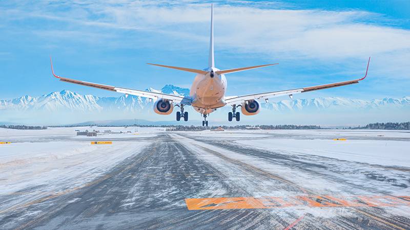 A view of a snowy runway and an airplane landing