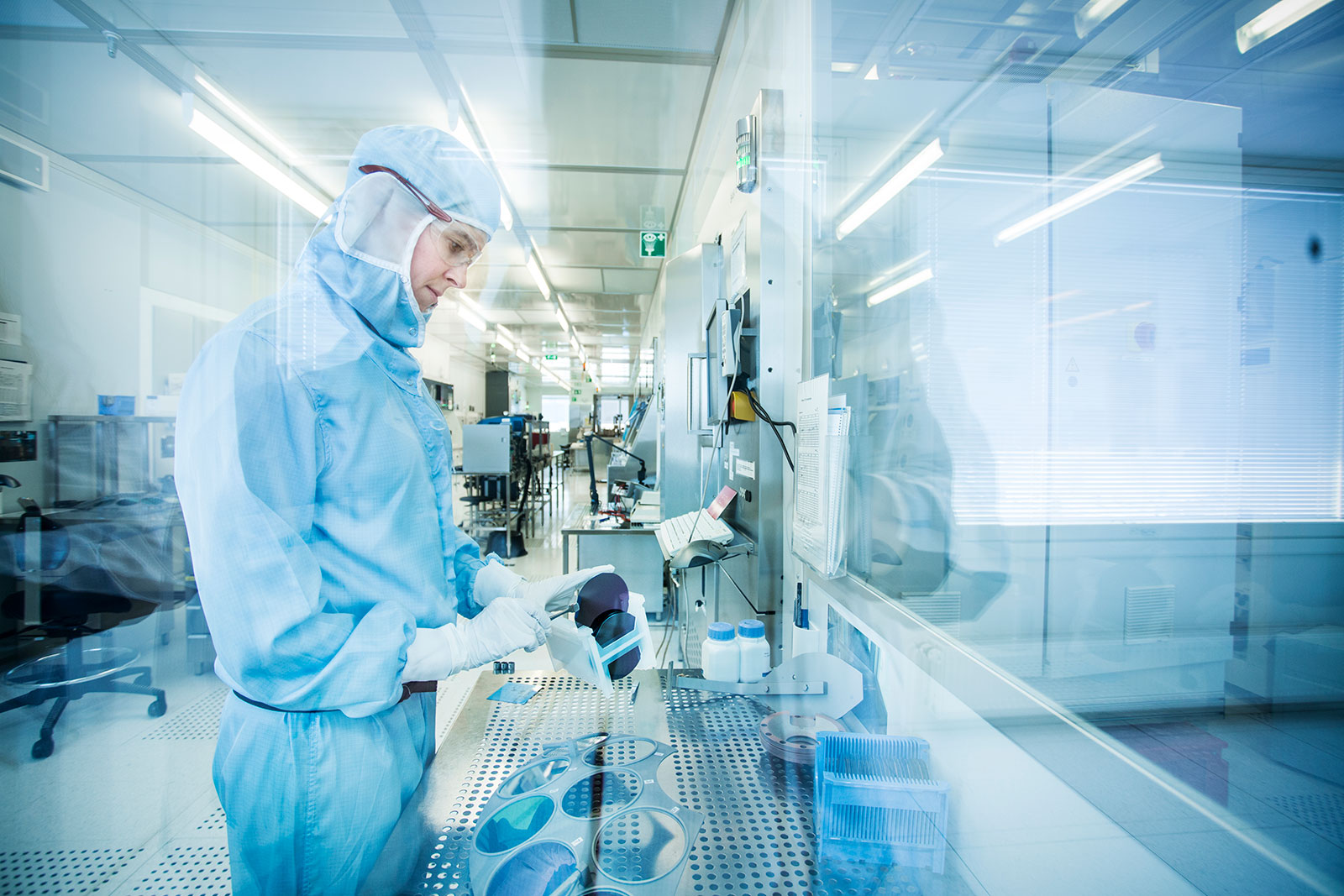A person with protective clothing in a cleanroom preparing sensor wafers.