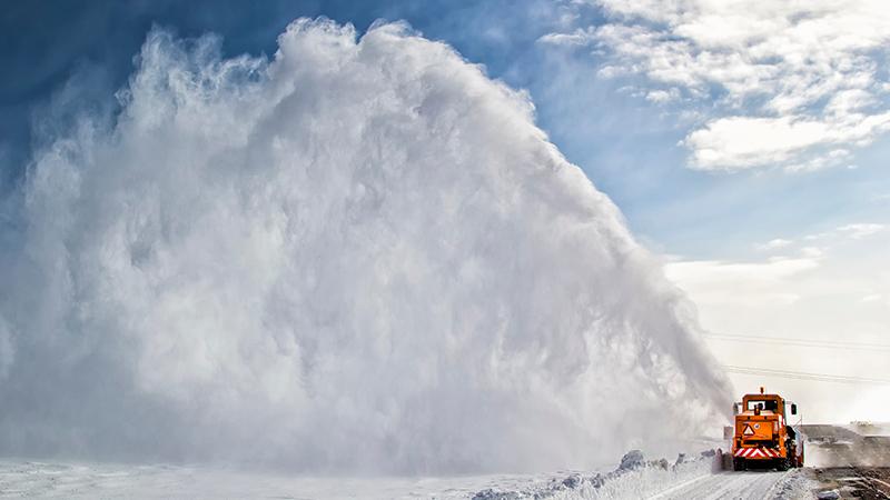 Snow-covered road cleaning by snow removal machine.