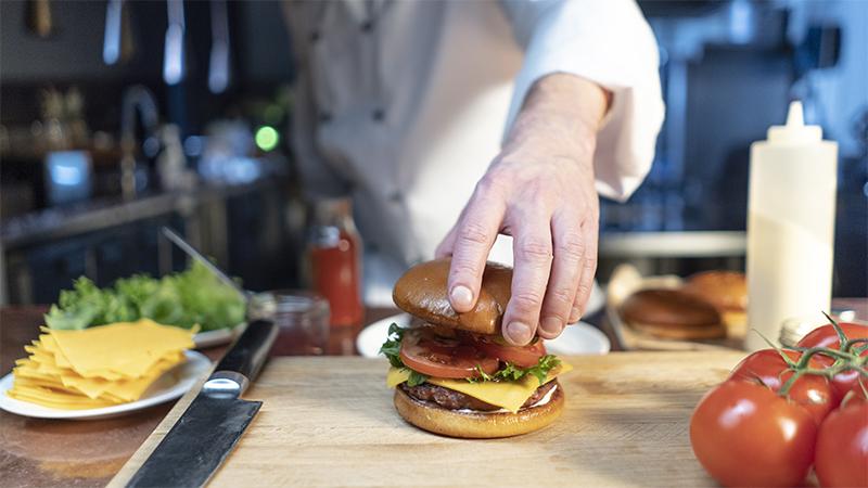 A chef assembling a hamburger