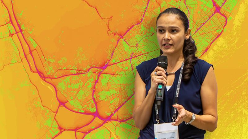 Laura Alku stands in front of a city map showing air quality index levels from Vaisala Xweather
