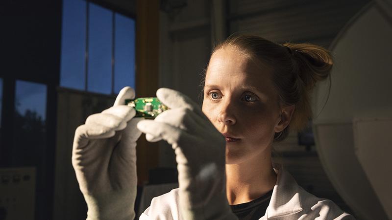Female engineer inspecting piece of electronic