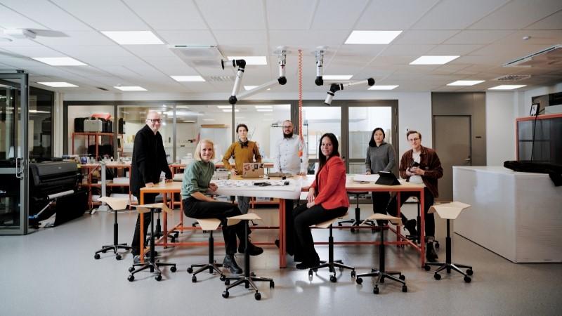 Team looking at the camera around table in Vaisala R&amp;D house Maker Lab