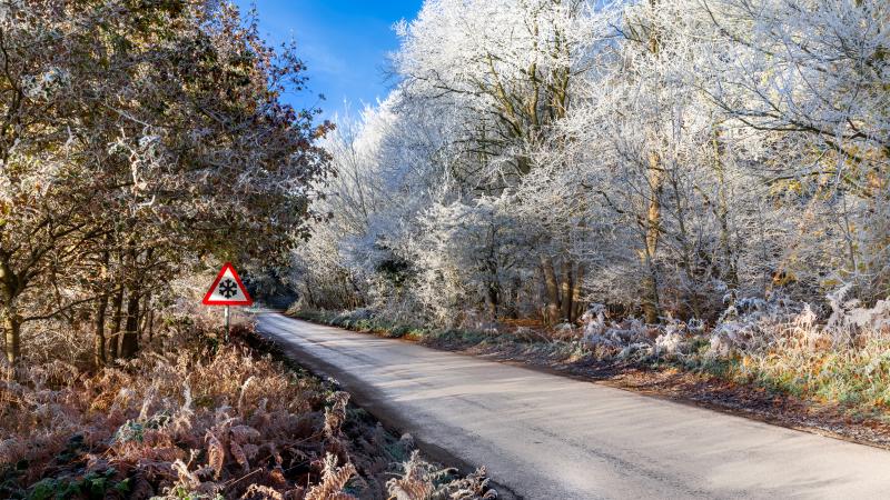 Snowy road with ice warning sign