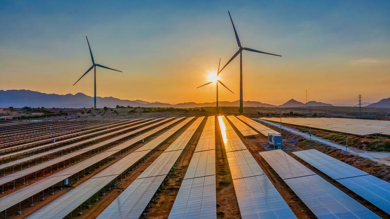 Aerial view of wind turbines and solar panels at sunrise