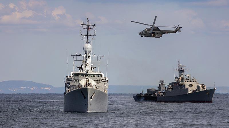 Military vessels at sea with helicopter above