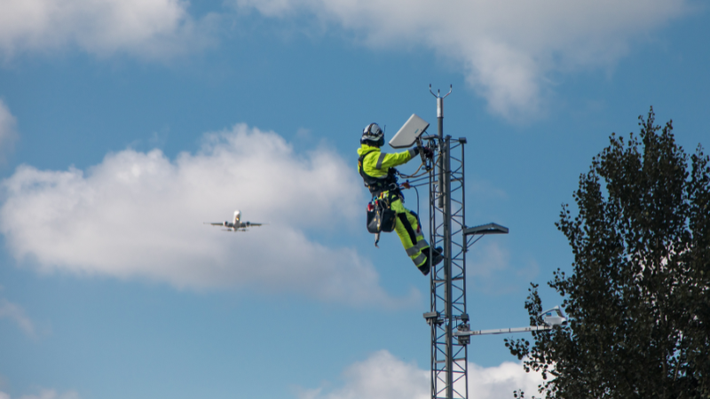 Field technician on RWS200 mast. Airplane in background. 