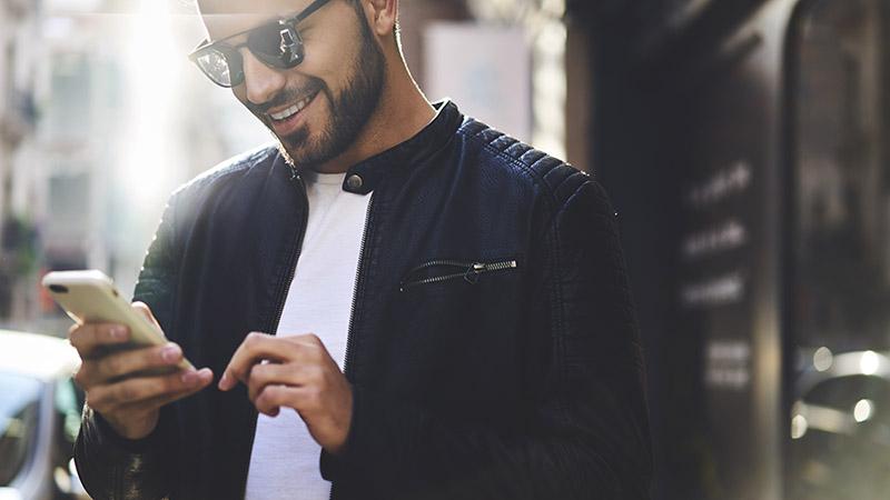 笑顔で携帯電話を見ている男性