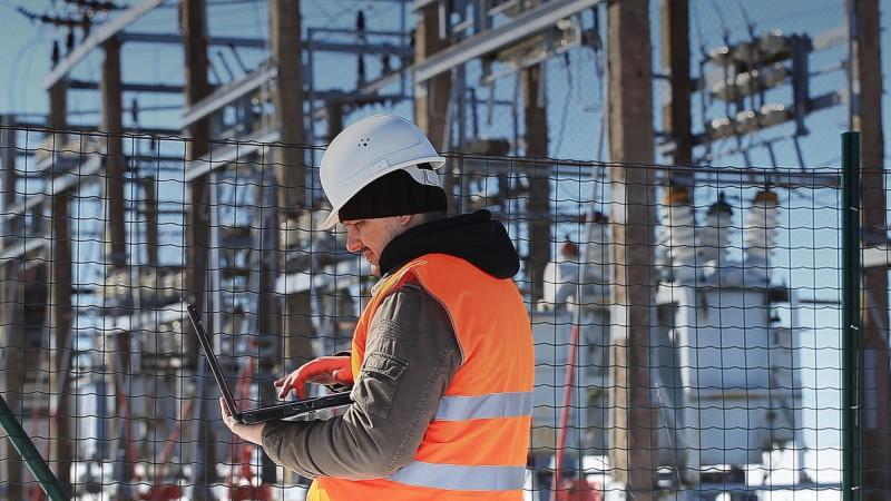 Man with laptop in front of power station
