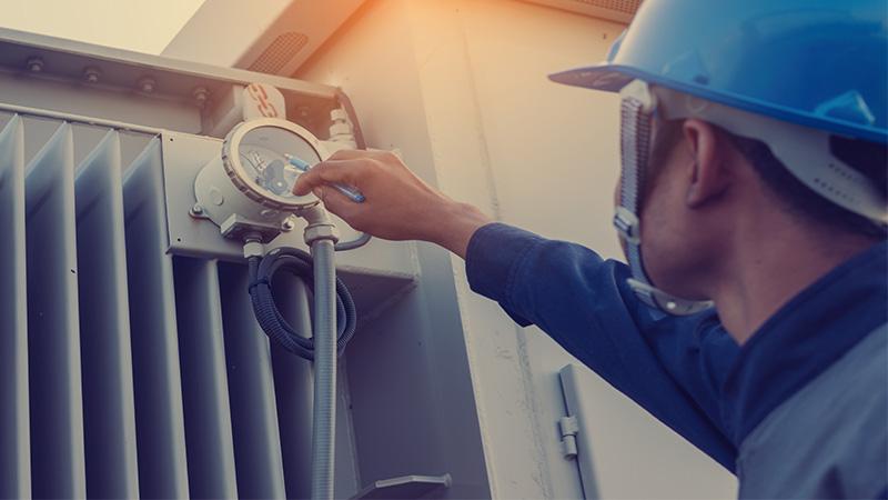 Un ingeniero o un electricista controlando el estado de la instalación de transformadores de alta tensión en el patio de transformadores.