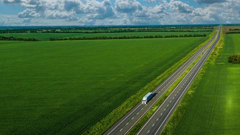 Aerial view truck driving on a road along the green fields 