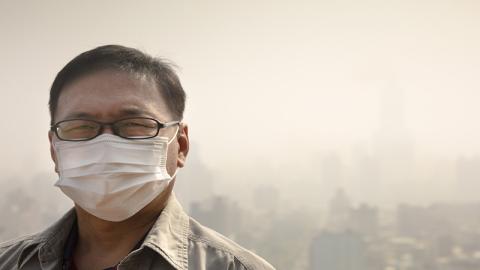 A man wearing a mask due to the smog in a city