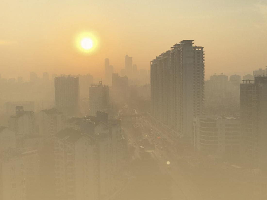 Sunlight peeking through smog in urban city skyline