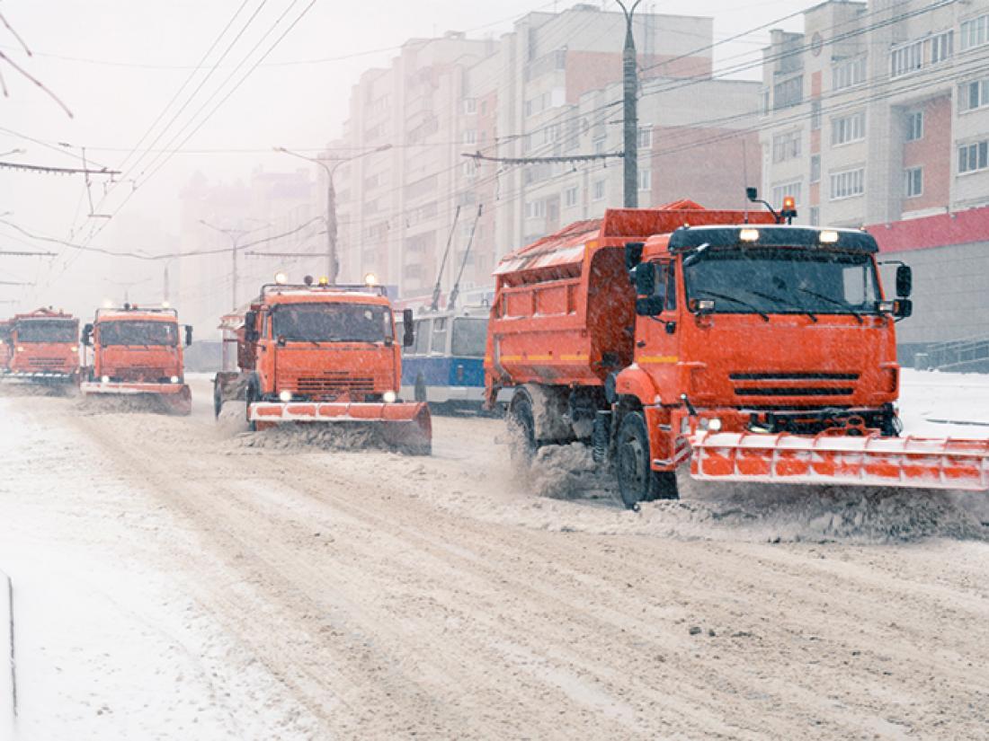 Line of snow plows clearing city roads during snow storm