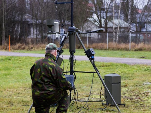 TacMet weather station with person in military clothing on laptop.