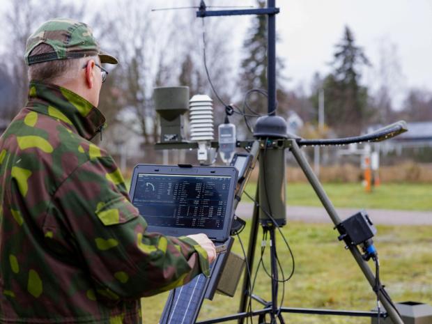 TacMet weather station with person in military clothing on laptop.