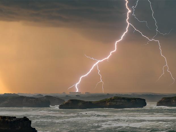 Stormy seascape with lightning over cliffs
