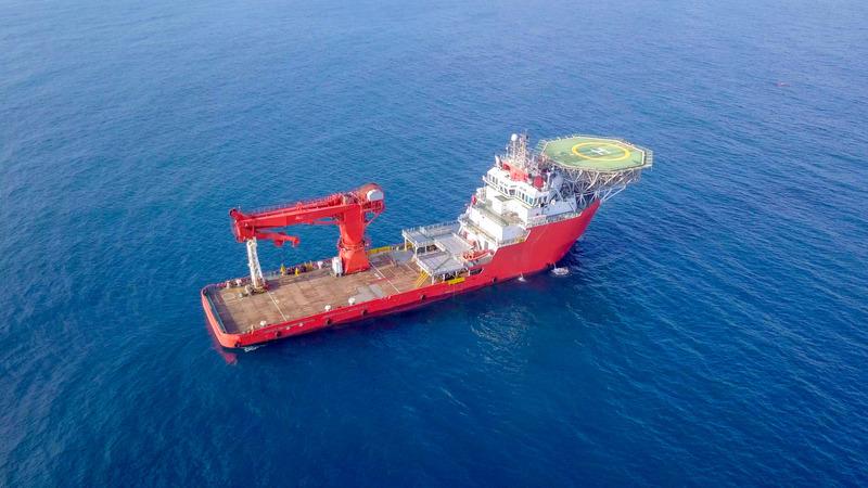 Offshore supply ship with a helipad and large crane.