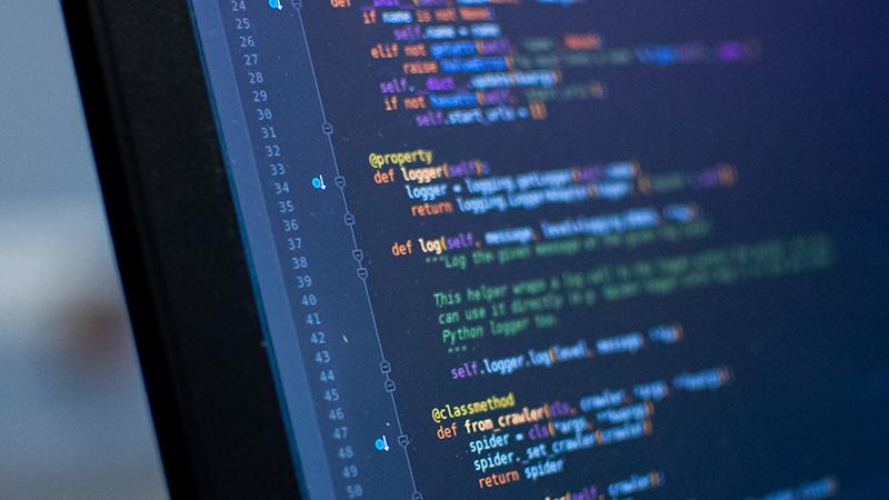 Ohjelmoija koodaamassa Python-, JavaScript-, HTML-koodia tietokoneen näytöllä.