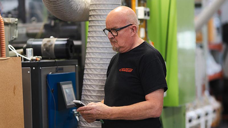 Camteamin Matti Majava tarkistamassa muovinkuivaimen kosteustasoa kannettavalla Vaisala Indigo80 ‑näyttölaitteella