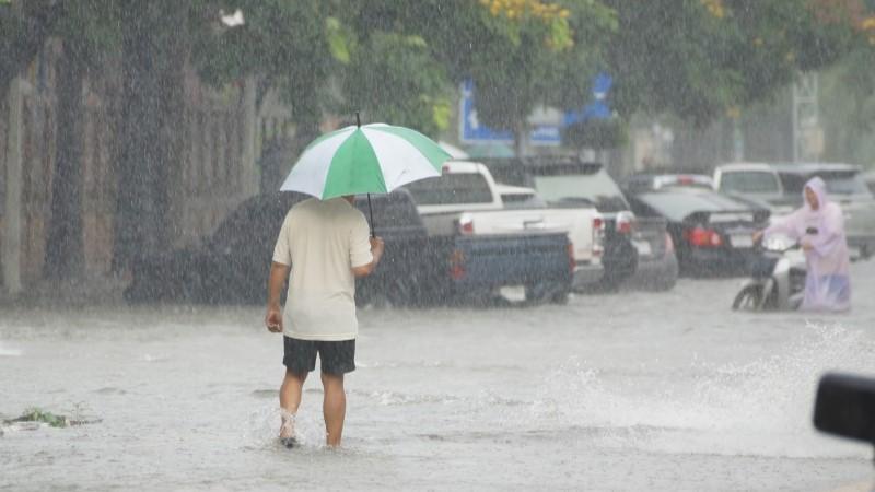Person with umbrella on a flooding street in heavy rain