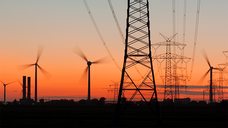 Power lines, pylons & wind turbines against evening sky