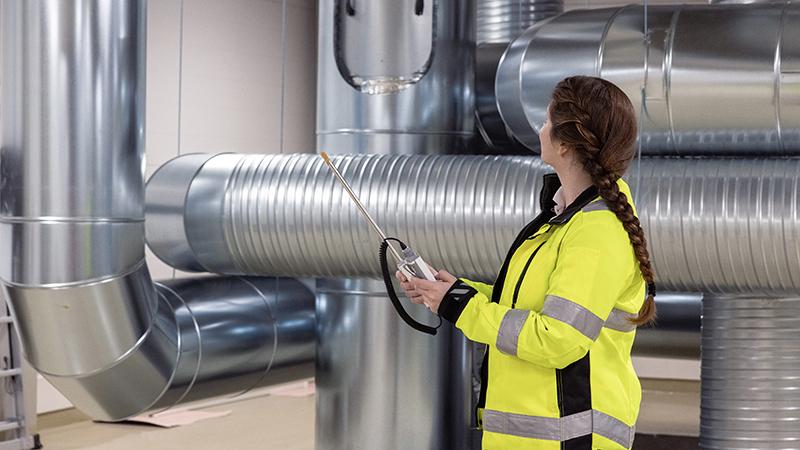 Person holding HM40 with HVAC ventilation ducts in the background.
