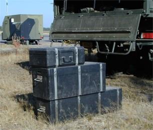 TacMet boxes on the ground behind military vehicle.