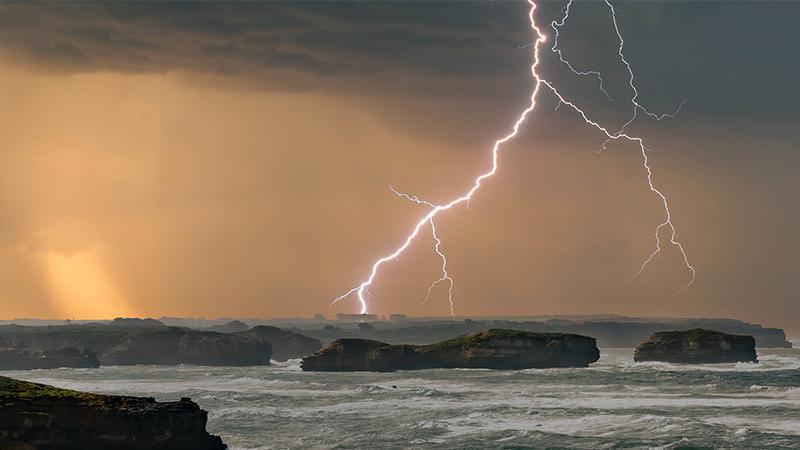Stormy seascape with lightning over cliffs
