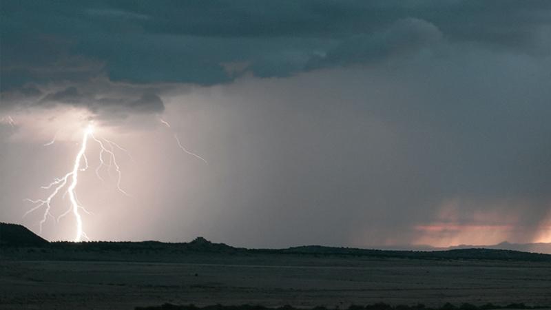 Landscape scenery with lightning and storm clouds over hills