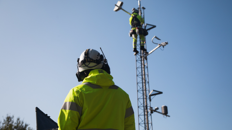 Image of field technicians servicing a Vaisala road weather station mast