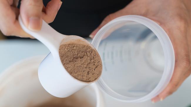 Woman pouring protein powder into a cup