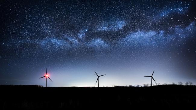Wind farm at night with the Milky Way visible in the sky
