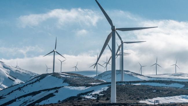 Wind turbines on a snow-covered rocky mountain peak