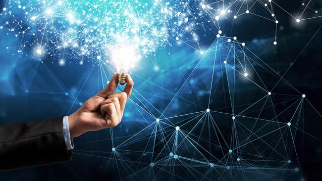 A man's hand holding a shiny light bulb