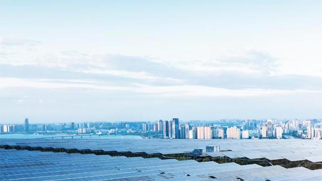 Solar panel field with city in background