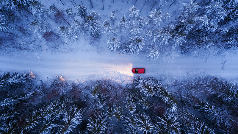 aerial view of a red car driving in winter road