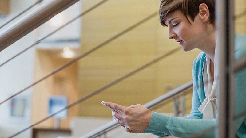 Woman sitting on stairs, holding mobile phone