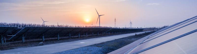 Sunset behind windfarm, solar panels 