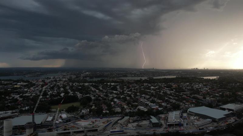 Thunderstorm over a city, lightning strikes the ground in the distance