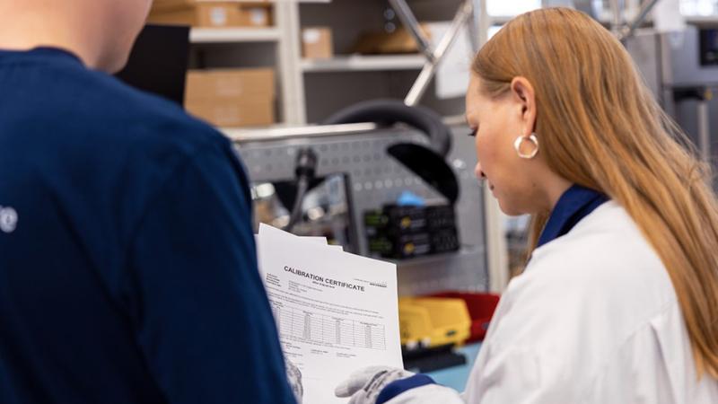 Two people looking at Vaisala's calibration certificate