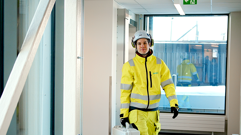 Field technician walking down corridor carrying equipment case.
