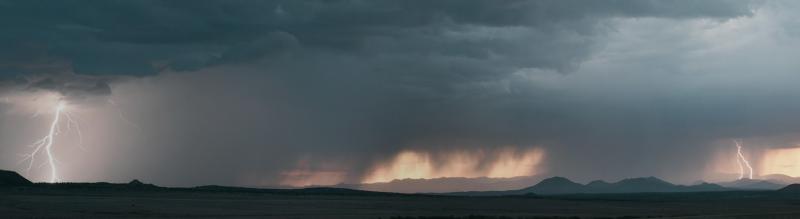 Landscape scenery with lightning and storm clouds over hills