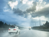 Drive car in rain on asphalt wet road. Clouds and sun.