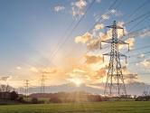 Electricity grid through a field at sunset