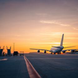 Airplane on runway with sunset in the background.